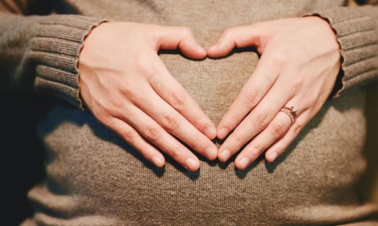 Pregnant hands over abdomen
