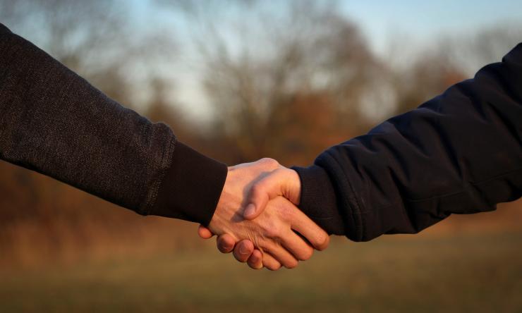 Close on hands of two people shaking hands while outside