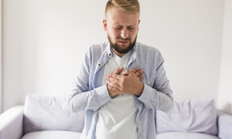 Man standing holding his chest in pain