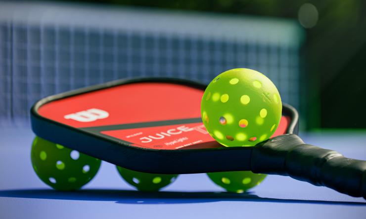 Red and black pickle ball paddle and green balls