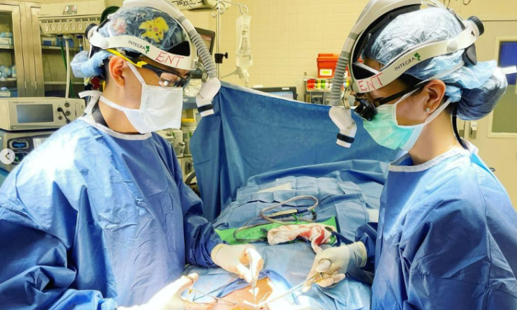 A pair of surgeons in the operating room working on a patient.