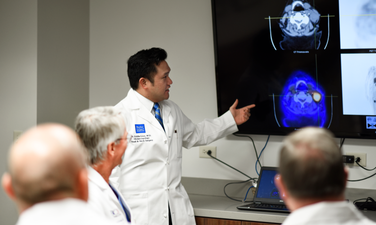 A doctor showing colleagues medical images on a large TV