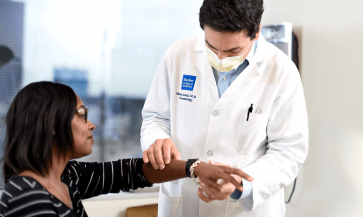 A dermatology physician examines a patient's arm