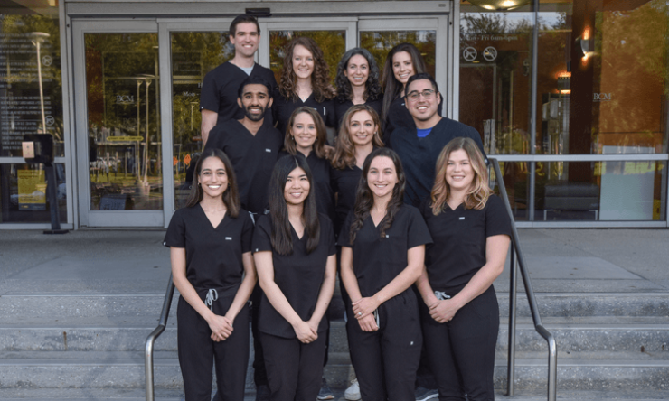 A group of Dermatology residents and fellows pose together while wearing scrubs