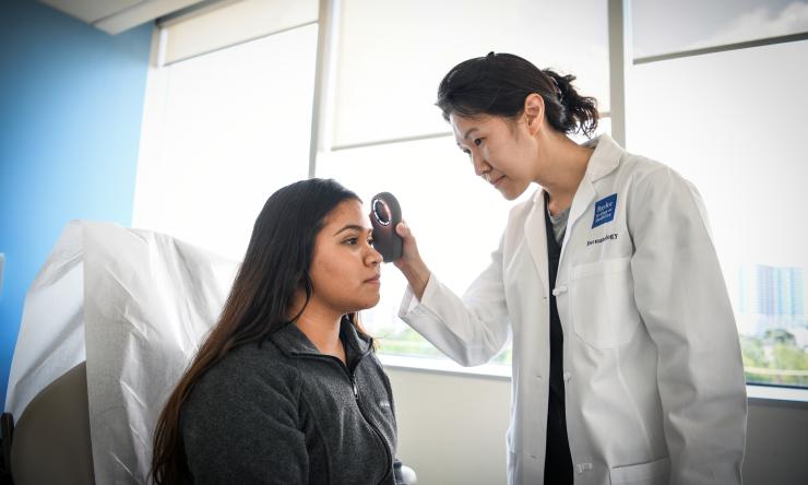 A Baylor dermatologist examines a patient's forehead
