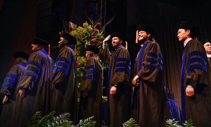 2023 PhD graduates process across the stage.