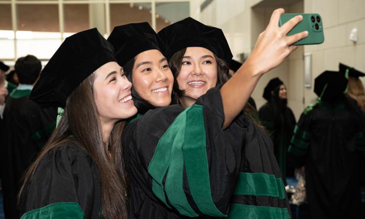 Three female 2023 medical school graduates take a selfie together. Three female 2023 medical school graduates take a selfie together.