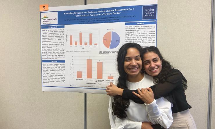 Dr. Anthoula Christodoulou and Dr. Ingrid Frydson (Class of 2023) hug next to their poster presentation