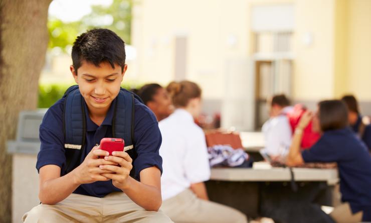 Male high school student using phone on school campus