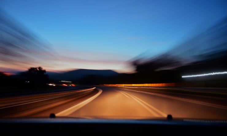 Photo taken at night from the drivers seat of a car of the road with blurred edges to signify driving and movement. 
