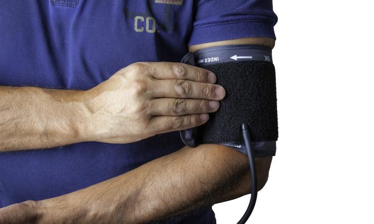 Photo of a man's arm wearing a blood pressure cuff. 