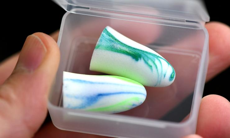 Close up photo of blue and white earplugs in a plastic box container. 