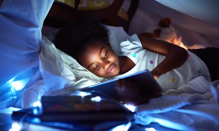 Girl looking at tablet in bed