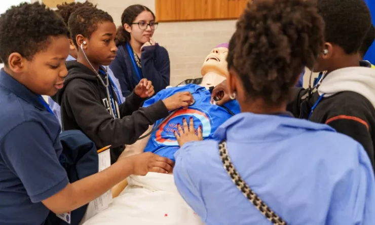 BCM Academy at Ryan students surround a simulation mannequin during a BCM open house 