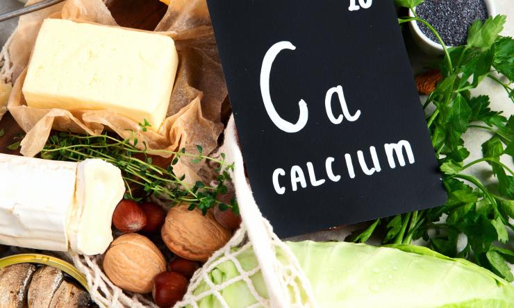 calcium periodic symbol with vegetables, nuts, and cheeses surrounding