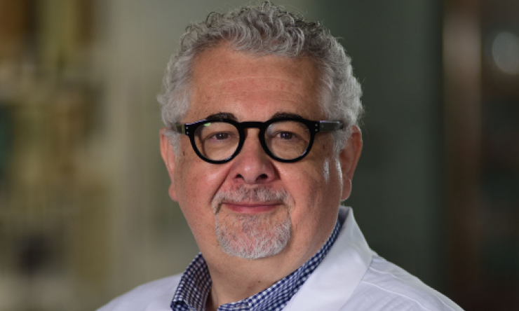 man with black round glasses and grey hair smiling