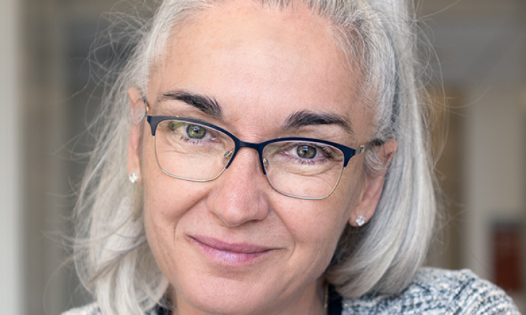woman with glasses on and hair in a ponytail smiling