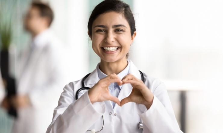 A female doctor holding her hands in the shape of a heart