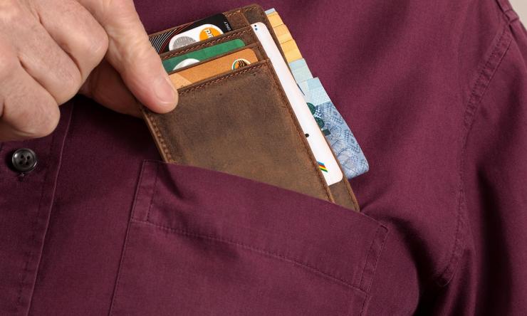 A close up photo of a man's front pocket with a bill fold holding credit cards to represent shopping addiction.