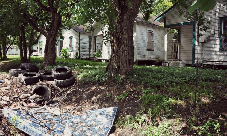 photo of houses in poor condition, trash, tires