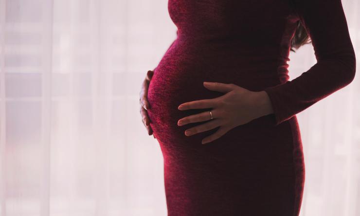 A pregnant woman holding her stomach.